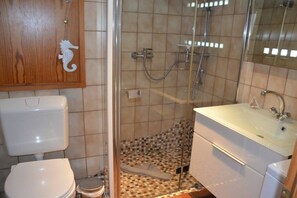 Un baño con inodoro, lavamanos y cabina de ducha.