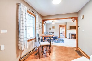 A hallway leading to a dining area with a table and chairs, a fireplace, and a ceiling fan. - Cozy Vintage Charm Located Between US 60 & I-64 (Ashland)