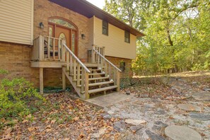 A two-story house with a brick facade, a wooden front porch, and a stone pathway leading to the entrance. - 3 Mi to Norfork Lake! Multi-Level Haven for Groups (Mountain Home)