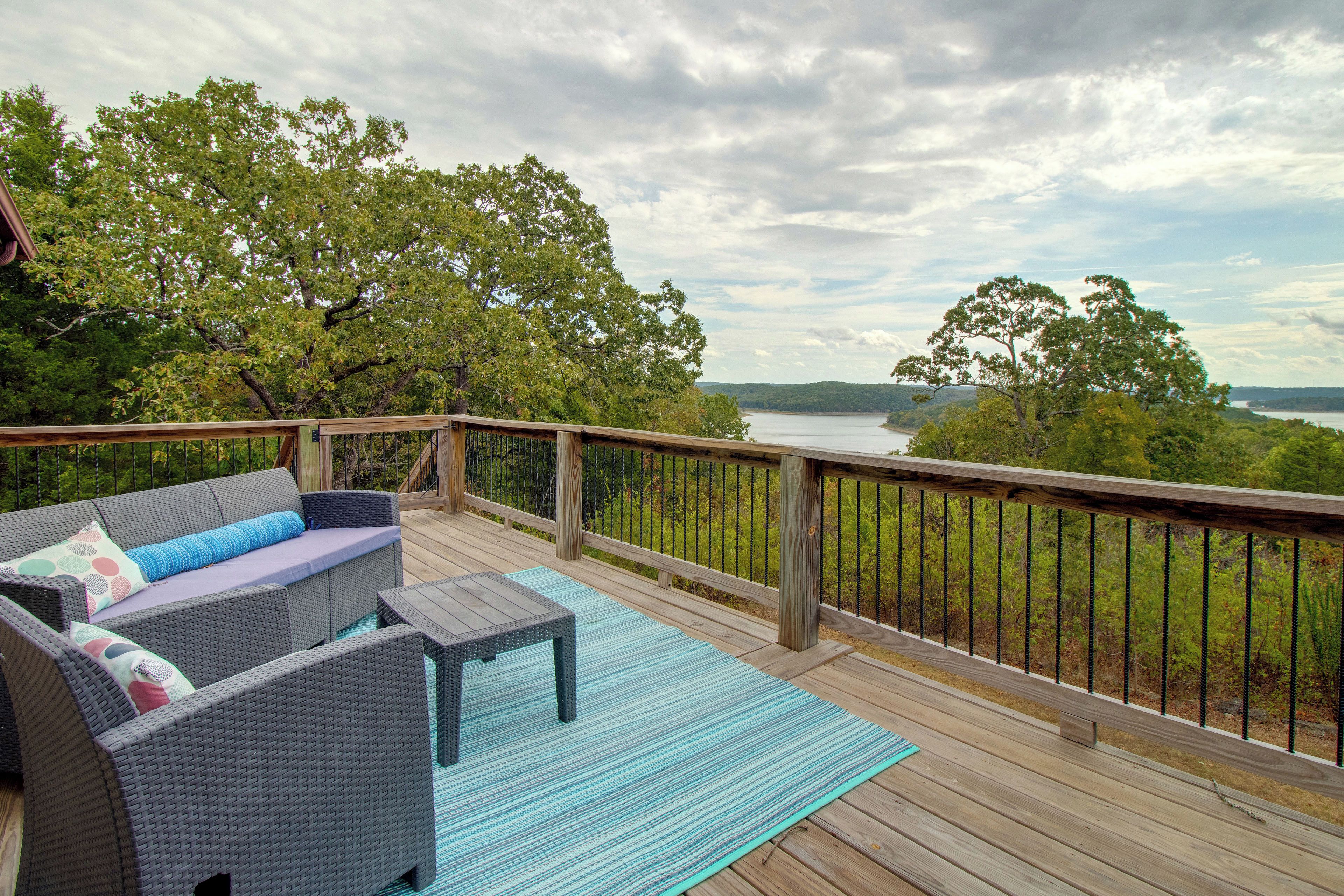 A deck with wicker furniture and a view of a lake.