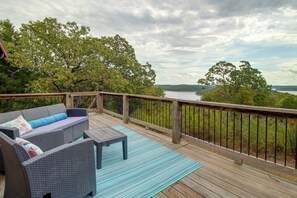 Um terraço com móveis de vime e vista para um lago.