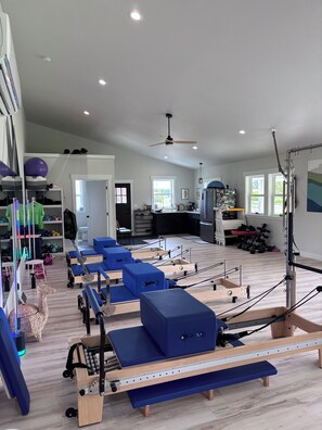 A fitness studio with Pilates equipment, a ceiling fan, and a large window. - Redtail Farm Guest House (Sequim)