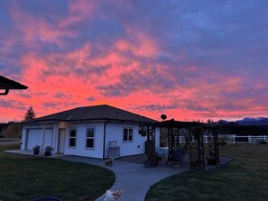 A house with a porch and a covered area, surrounded by a fenced yard. - Redtail Farm Guest House (Sequim)