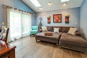 A living room with a brown sectional sofa, a teal armchair, and a wooden coffee table. - Steps to Lake! Home w/ Deck & Views in Conesus (Conesus)