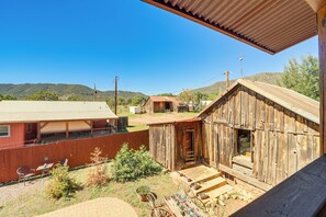 Une grange rustique, avec une façade en bois et un toit en métal, entourée d’une cour clôturée, agrémentée d’une terrasse en briques et de plantes en pot.