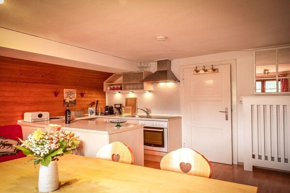 A compact kitchen with a central island, a built-in oven, and a white door with a radiator.
