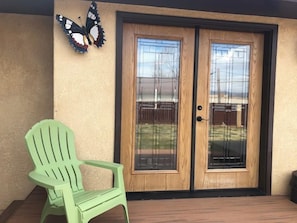 A wooden door with glass panels, a green chair, and a butterfly decoration on the wall. - Poncha Springs Home Near Salida & Buena Vista (Poncha Springs)