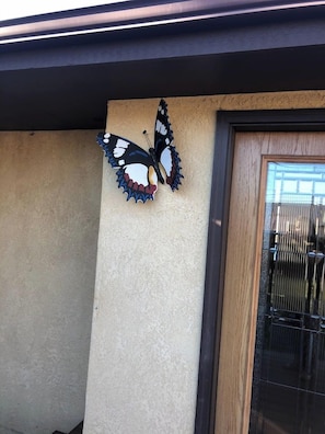 A building exterior with a butterfly decoration on the wall and a door with a metal gate. - Poncha Springs Home Near Salida & Buena Vista (Poncha Springs)
