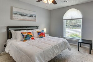 Ein Schlafzimmer mit Bett, Deckenventilator, Fenster mit Jalousien und einem Gemälde an der Wand.