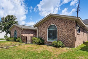 A two-story brick house with a front entrance, a garage, and a small front yard. - Modern Galveston Retreat Near Beach, Strand & Pier (Galveston)