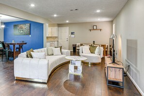 A modern living room with a sofa, a coffee table, and a dining area with chairs. - Modern Galveston Retreat Near Beach, Strand & Pier (Galveston)