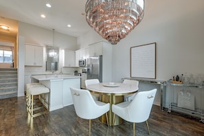 A modern kitchen with white cabinetry, stainless steel appliances, a marble island, and a chandelier. - Modern West Des Moines Townhome - Family Friendly! (West Des Moines)