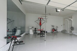 Ein Fitnessraum mit Trainingsgeräten, einem Spiegel und einem Ventilator.