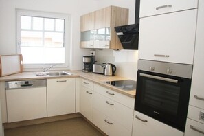 A modern kitchen with white cabinetry, a Bosch oven, and a coffee maker. - Terraced house with 2 bedrooms (Sylt Ost\/ Tinnum)