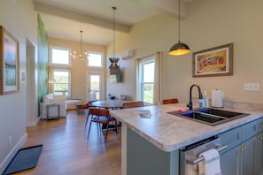 A modern kitchen with a large island, a dining area with a table and chairs, and a living space with a sofa and a view of the outdoors. - Hike, Explore & Unwind: Scenic Blue Ridge Escape (Floyd)