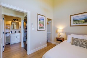 A hotel room with a bed, a nightstand, a lamp, a painting, a bathroom with a mirror, and a wardrobe. - Hike, Explore & Unwind: Scenic Blue Ridge Escape (Floyd)