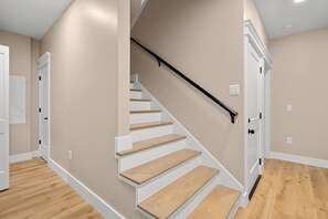 A staircase with wooden steps and a black handrail, leading to a white door. - Brand New Retreat Private Pool & Golf Simulator (Hilton Head)