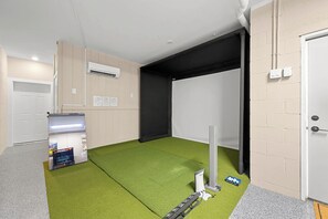 A room with a green carpet, a white door, and a black partition. - Brand New Retreat Private Pool & Golf Simulator (Hilton Head)