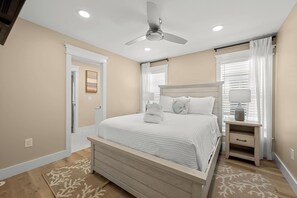 A bedroom with a bed, bedside table, lamp, and ceiling fan. - Brand New Retreat Private Pool & Golf Simulator (Hilton Head)