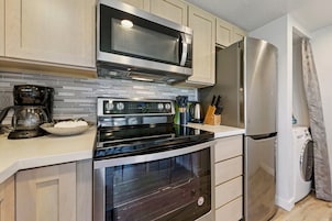 Una cocina moderna con un refrigerador de acero inoxidable, un microondas, un horno y una cafetera.