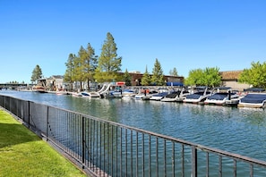 A marina with boats docked along a waterfront, a metal railing in the foreground, and buildings in the background. - 489 Tahoe Keys Blvd, Unit 69 1 Bedroom Condo (South Lake Tahoe)