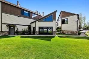 A modern two-story house with a stone foundation, a front door, and a well-maintained lawn. - 489 Tahoe Keys Blvd, Unit 69 1 Bedroom Condo (South Lake Tahoe)