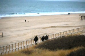 A beach with a metal railing, a few people walking, and the ocean in the background. - Terraced house with 2 bedrooms (Sylt Ost\/ Tinnum)