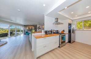 Una cocina moderna con una isla central, electrodomésticos de acero inoxidable y vistas al exterior.
