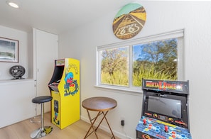 Ein Zimmer mit Spielhallenspielen, einem Fenster mit Blick auf Bäume und einer Tür.