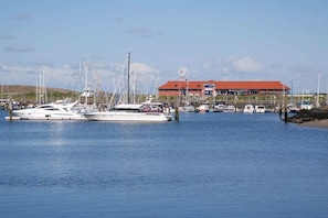Een jachthaven met verschillende jachten in de haven, een gebouw met een rood dak en rustig water.