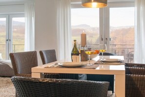 A dining area with wicker furniture, a table set with plates, glasses, and a bottle, and a candle. - Holiday apartment *blanco* Willingen (Willingen)