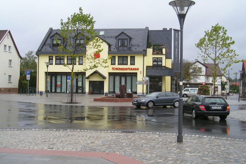 A building with a sign reading 'Kreissparkasse' on the facade, a paved street with cars, and a lamppost.