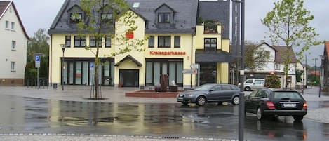 A building with a sign reading 'Kreissparkasse' on the facade, a paved street with cars, and a lamppost.