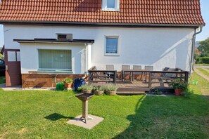 A house with a tiled roof, a patio with outdoor furniture, and a small garden area. - Holiday apartment with 2 bedrooms (Bad Tabarz)