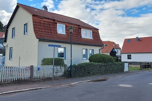 A two-story residential building with a red-tiled roof, a white picket fence, and a street sign indicating 'Schwarzkaser Straße.' - Holiday apartment with 2 bedrooms (Bad Tabarz)