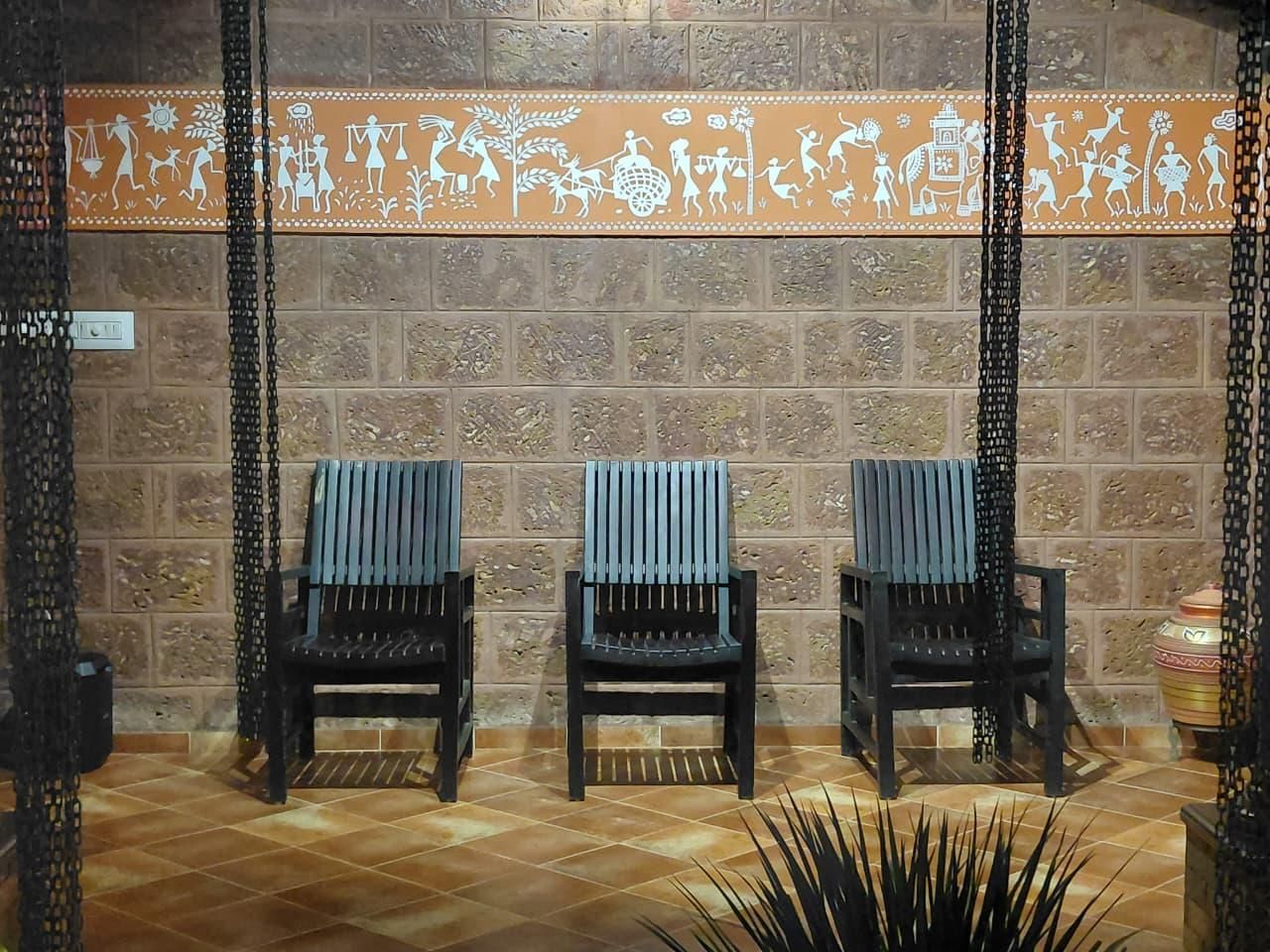 Tres sillas negras con cojines azules frente a una pared con un borde decorativo.