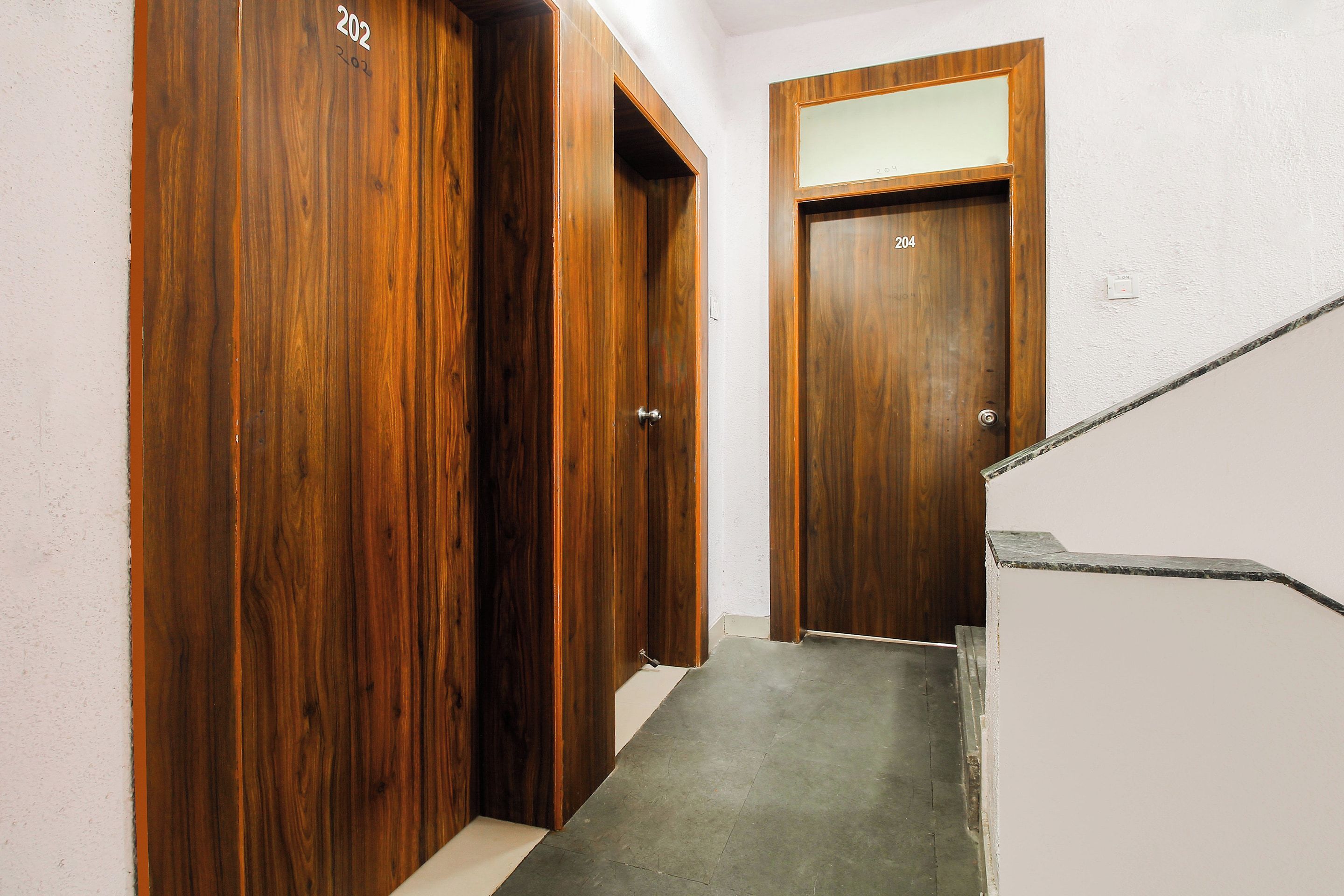 A hallway with wooden doors numbered 202 and 204, leading to a staircase.