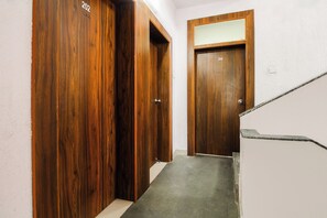 A hallway with wooden doors numbered 202 and 204, leading to a staircase. - Hotel O Galaxy Near INOX (Pune)