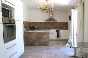 A modern kitchen with built-in appliances, a central island, and a chandelier. - The Commandery & The Doves (Saint-Gilles)