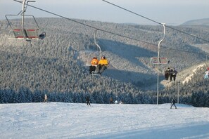 A ski lift with passengers and a snowy mountain landscape. - Benni's Toboggan Run (Oberhof)