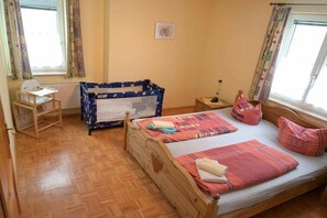A bedroom with a wooden bed, a crib, a desk, and a radiator. - Benni's Toboggan Run (Oberhof)