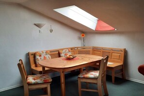 A dining area with a wooden table and bench seating, a skylight, and a vase with a flower. - Adalbert Stifter Holiday Village (Hauzenberg)