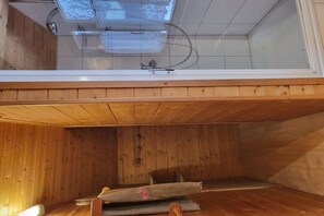 A room with a sloped ceiling, wooden walls, a skylight, and a visible plumbing system.