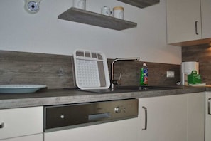A kitchen with a built-in dishwasher, a sink, and a shelf above the counter. - Holiday apartment with 2 bedrooms (Norddeich)