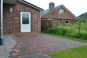 A brick house with a white door and a paved patio area. - Holiday apartment with 2 bedrooms (Norddeich)