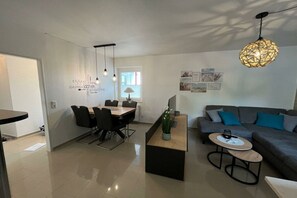 Een moderne woonkamer met een eethoek, een bank en een salontafel.