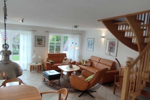 Un salon comprenant un ensemble de canapés, une table basse, une lampe et un escalier.
