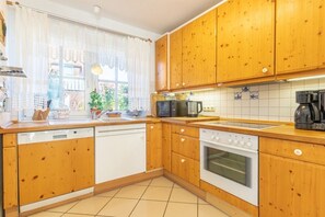 Une cuisine avec des meubles de rangement en bois, un lave-vaisselle, un four et une machine à café.