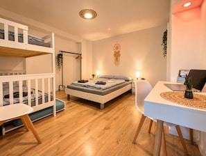 A modern bedroom with a bunk bed, a single bed, a desk with a laptop, and a bedside lamp. - Modern Apartment with Stunning Mountain Views @ Sunrise Pfronten (Pfronten)