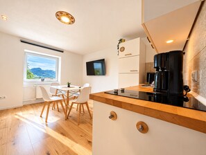 Et moderne køkken med træbordplade, integrerede hårde hvidevarer og spiseplads med udsigt over det fri.